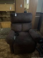 Front view of brown upholstered recliner with wired remote on seat