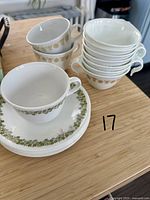 Photo showing stacked cups and matching saucers/sideplates with green and golden floral patterns.