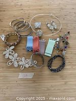 Overview of the entire lot showing bracelets, earrings, watch bands, and a floral hair accessory on a wooden surface.