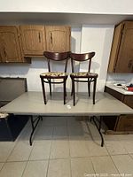 Photo of the solid wood folding table with two wooden chairs placed on top to show size and condition.