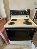 Front view of white Moffatt electric stove with four coil burners and black oven door.