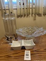 Front view showing two clear pepper and salt mills with stands, a large clear glass bowl with petal design, and a white ceramic dual dip bowl spaced on table.