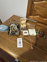 Overview of various jewelry pieces on a wooden surface, including boxes holding rings and earrings and a blue ceramic tray.
