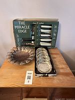 Silver plated coasters in original box, Miracle Edge knife set in vintage packaging, silver plated bowl shown on wooden surface