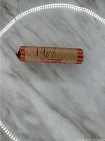 Photo of a single roll of 1968 pennies wrapped in brown paper with red stripes, handwritten year '1968' on the wrapper.