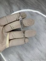 Front side of the 7 1/2 inch 925 silver flower bracelet held in hand with gloves.