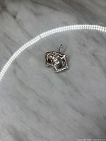 Close-up photo of the sterling silver panther head bust pendant showing detailed facial features and open mouth on marble surface.