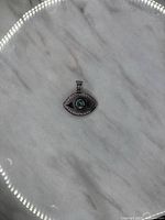 Full view of the evil eye pendant on a marble surface showing size and shape.