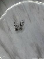 Pair of 925 silver leverback drop earrings with circular clear stones on marble background