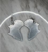 Photo of a pair of aluminum earrings shaped like the map of Africa.