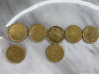Front side of seven Netherlands 20 Euro cent coins showing denomination and date.