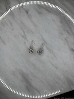 Pair of Silpada sterling silver 925 earrings with floral circular dangle on a light marble background.