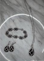 Full view of the 3-piece jewelry set on a marble surface under circular ring light reflection.