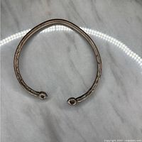 Top down view of one vintage sterling silver open cuff bangle bracelet showing textured surface and rounded ends