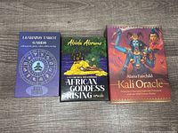 Three card decks including Learning Tarot Cards, African Goddess Rising Oracle, and Kali Oracle in original boxes with colorful cover artwork