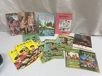 Twelve vintage Chinese children's soft cover books arranged on flat surface showing variety of colorful illustrated covers with children and traditional scenes.