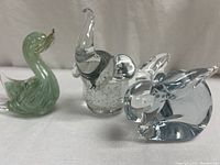 Front angle view showing green swan, clear elephant, and clear rabbit figurines.