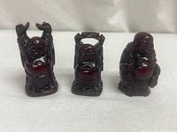Front view of 3 dark cinnabar Buddha mini sculptures showing distinct poses and glossy finish.