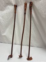 Full view of three antique braided leather whips standing upright