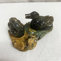 Hand-carved jade sculpture showing two Chinese ducks with detailed carving and natural stone colors.