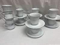 Multiple sets of Crown Ming China vintage porcelain cups stacked on matching saucers showing varied floral patterns and silver rims
