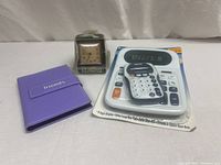 Vintage alarm clock and packaged dual calculator set on white surface