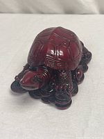 Front view of the carved cinnabar lacquer turtle figurine showing detailed shell and coins base