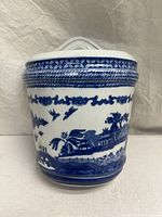 Front view showing classic Blue Willow pattern with birds, bridge, and houses in transfer blue on white ceramic.
