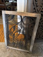 Close up view of one screen panel showing weathered wooden frame and black metal circular design insert.