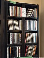 Wide view of eight cubby dark brown shelves filled with upright CDs showing spines with artist and album titles.