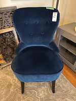 Front view of blue velvet tufted accent chair with wooden legs.