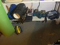 Wide view of yoga mat, foam rollers, weights, and bike accessories on basement shelf