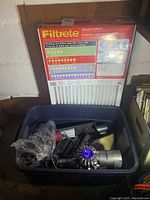 Filtrete allergen defense furnace filters displayed upright with packaging details visible, plastic crate in foreground containing various Dyson vacuum parts