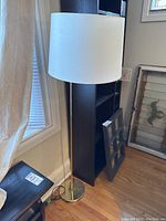 Full view of the floor lamp showing its height, metal base, and lampshade