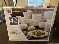 Photo of the original box showing all dishes in the Mikasa Swirl 40-piece set including plates, bowls, and mugs arranged with salad on plate and bowls full of fruit on the box image.