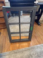 Front view of the six-panel wood framed mirror standing on hardwood floor.