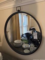 Front view of the round mirror on the wall showing some plates and mugs reflected.