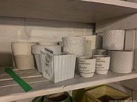 Multiple white ceramic plant pots on shelf showing different textures and sizes