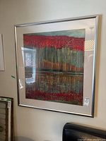 Front view of framed abstract print hanging on wall with red, orange, blue vertical stripes.