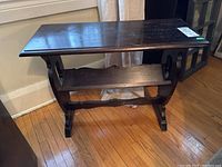 Photo showing the front of the vintage wood side table with a visible lower V-shaped shelf and scuffed finish.