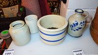 Three Robinson stoneware containers displayed on a white surface including a decorated jug, a large jar with blue bands, and a plain container.