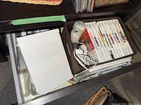 Photo of drawer with white Wii game cases, cords, accessories and manuals showing multiple game titles.