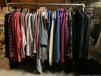 Photo showing the full clothing rack with assorted ladies clothes including shirts, knitwear, ponchos, and coats in a range of colors and styles