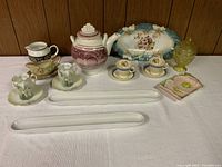 Full lot with teapot, cups and saucers from Germany (green) and England (blue), serving trays, olive/pickle trays, yellow glass bowl, Tetley Tea creamer, and decorative plates.