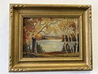 Frontal view of the antique gilt frame with the oil painting on board showing autumn trees and a lake, signed by Jay Russel.