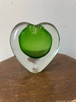 Front-facing image showing the clear heart-shaped glass with an apple green interior core.