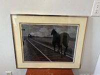 Framed black and white art print showing horse on tracks with approaching train, view from straight on.