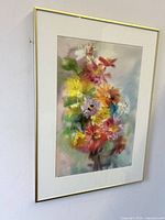 Framed vibrant watercolour painting of flowers on wall, showing colors and frame details.