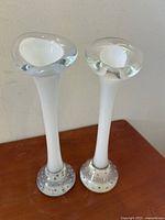 Two slender white and clear art glass vases with bubble bases on wood surface