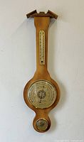 Full view of the wooden wall barometer weather station showing the thermometer, barometer, and hygrometer.